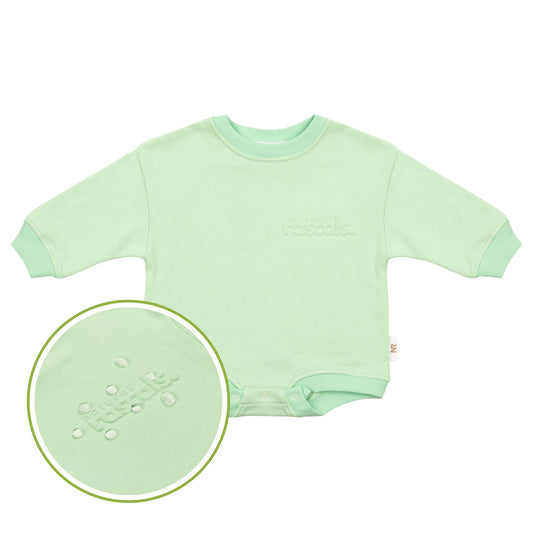 Child in mint green spill resistant outfit posing drinking a sippy cup