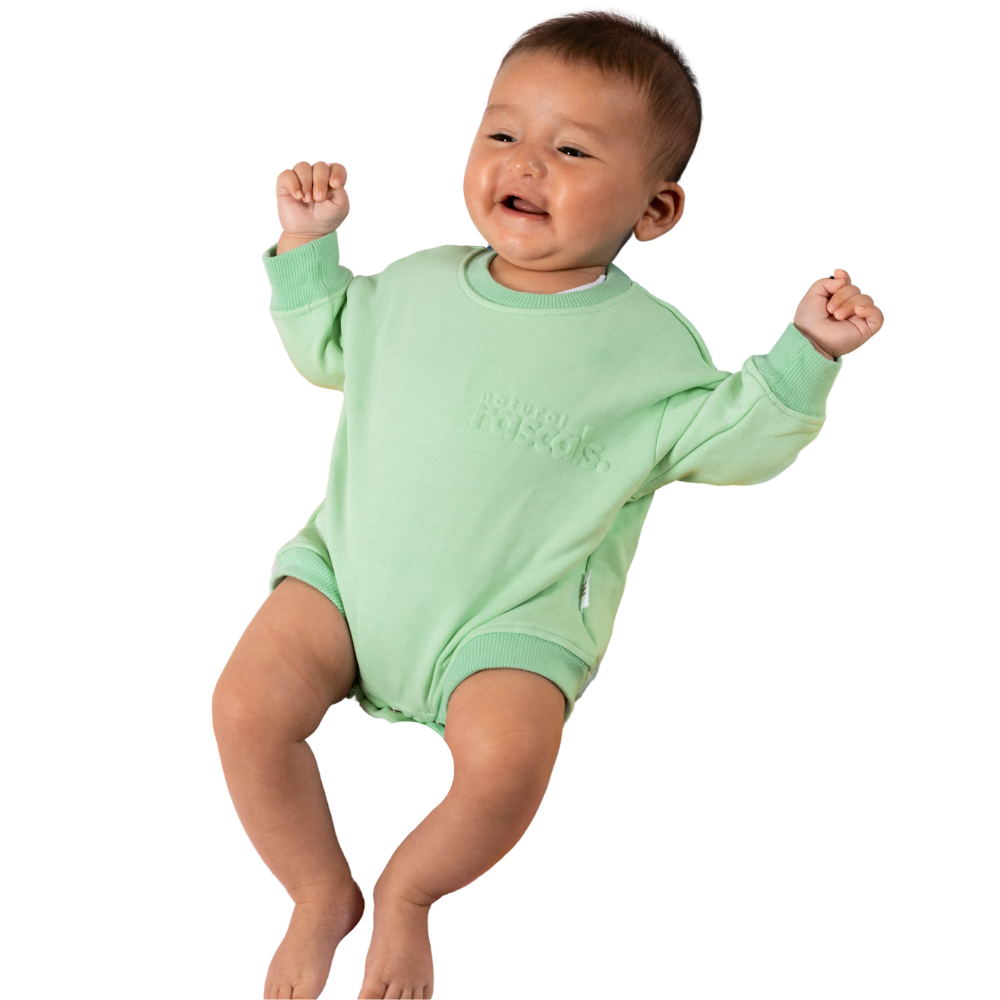 Baby in mint green spill-resistant onesie romper by Natural Rascals on transparent background.