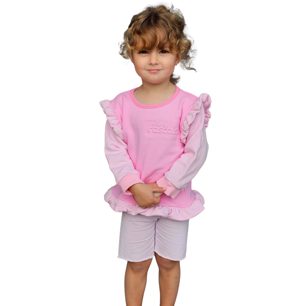 Child wearing a raspberry candy pink spill resistant outfit with ruffled sleeves by Natural Rascals on a transparent background