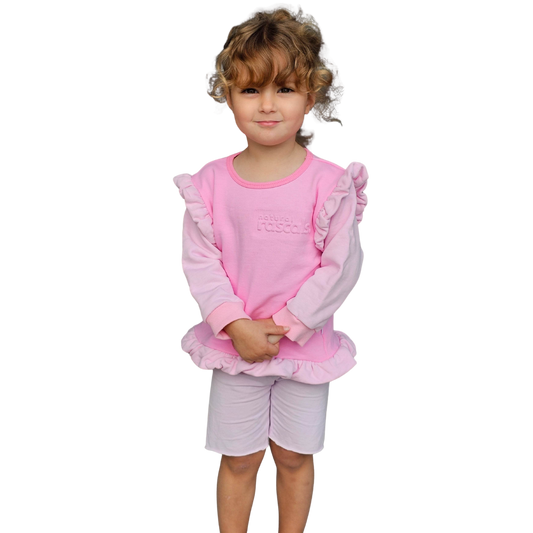 Child wearing a raspberry candy pink spill resistant outfit with ruffled sleeves by Natural Rascals on a transparent background