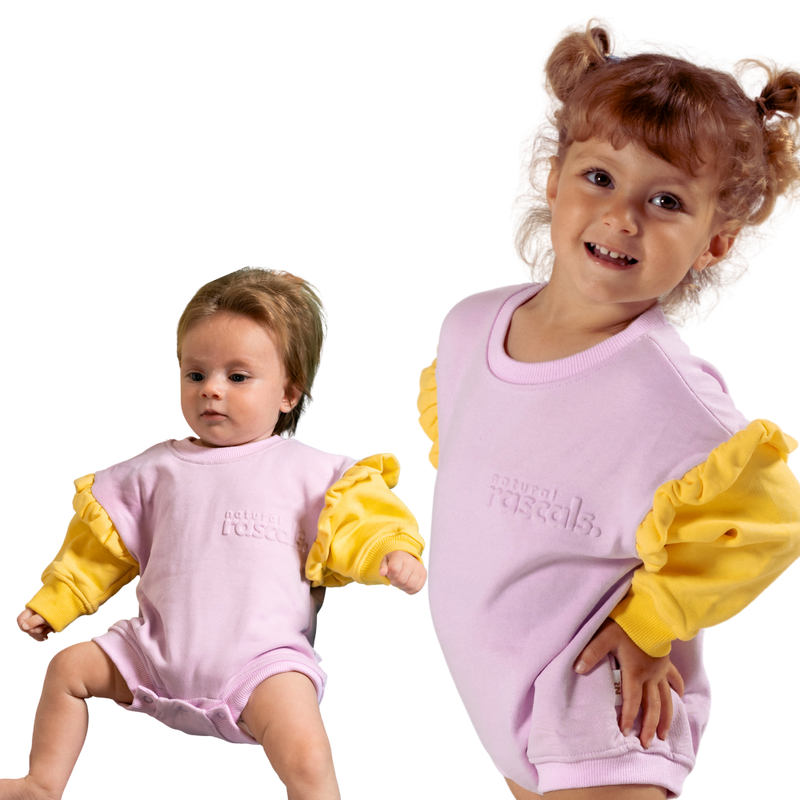 Two children wearing matching pastlel lavender and sunshine yellow baby, toddler rompers that are spill resistant by Natural Rascals