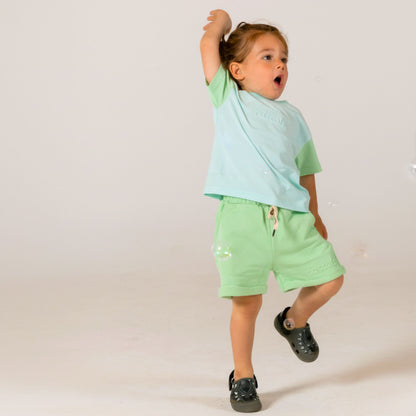 Happy child jumping in excitement wearing mint green and matching airy blue and mint green spill resistant t shirt by Natural Rascals