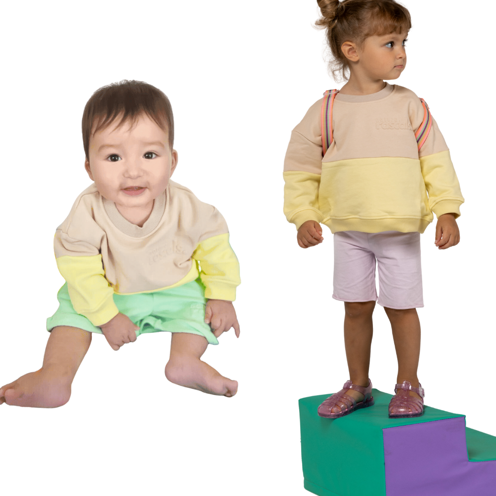 Two children wearing spill resistant sweats in lemonade yellow and oat on a transparent background