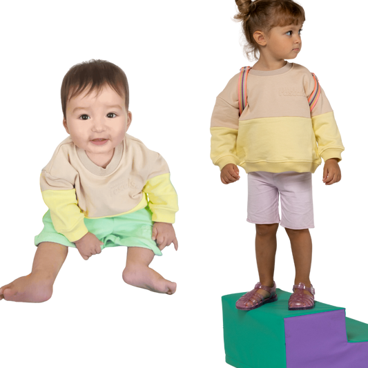 Two children wearing spill resistant sweats in lemonade yellow and oat on a transparent background