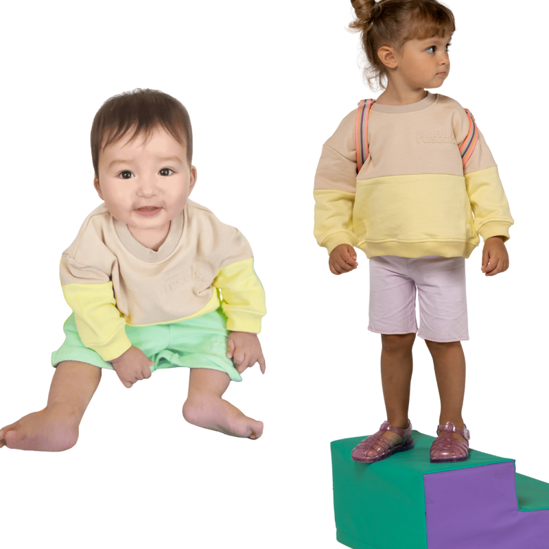 Two children wearing spill resistant sweats in lemonade yellow and oat on a transparent background